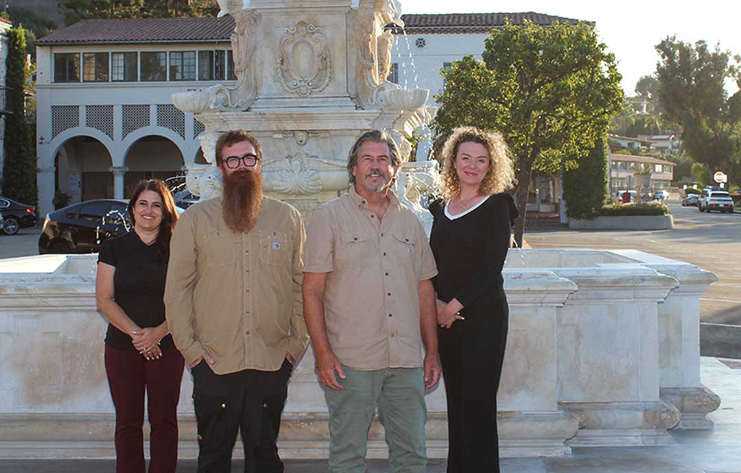2 men and 2 women standing in front of a large outdoor fountain