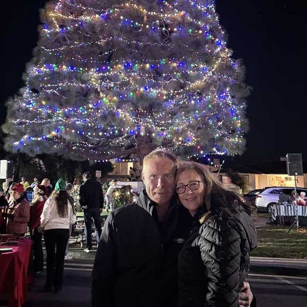 man and woman standing in front of very big christmas tree