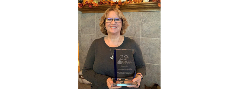 mary mclachlan malaga staff member holding her crystal 20 year anniversary award