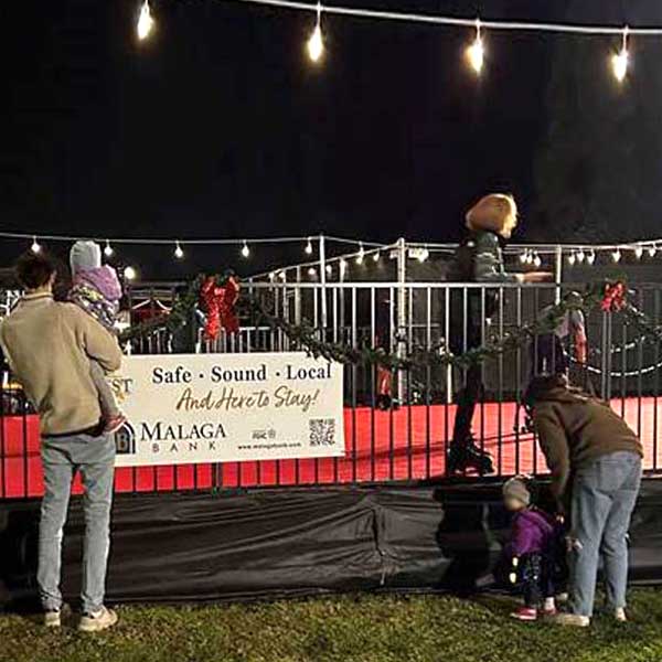 family with young children watch an outdoor skating rink