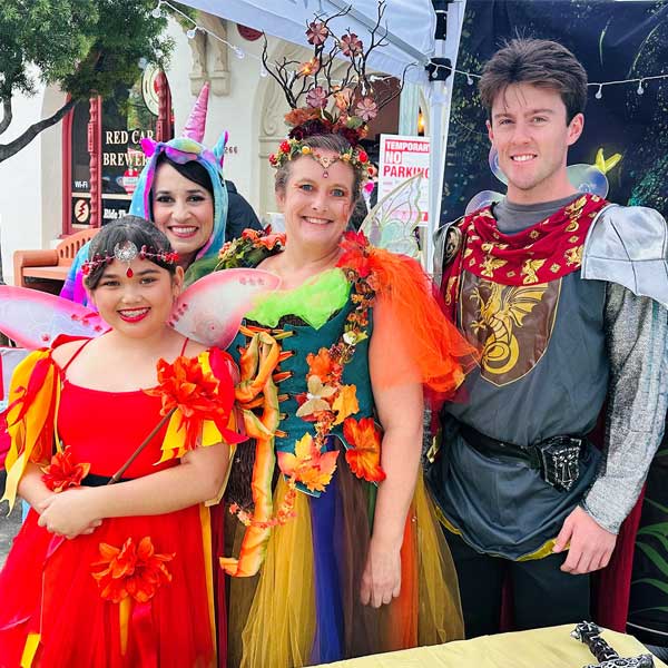 small girl dressed as a woodland fairy, woman dressed as a unicorn, woman dressed as a woodland fairy, and man dressed as a knight