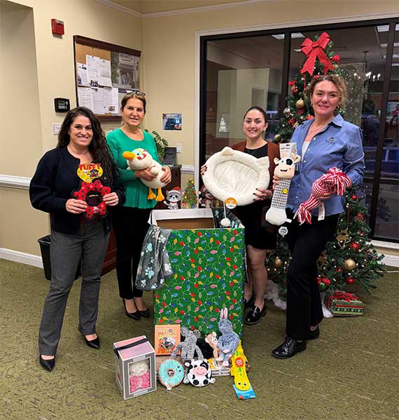 women holding toys around a christmas tree