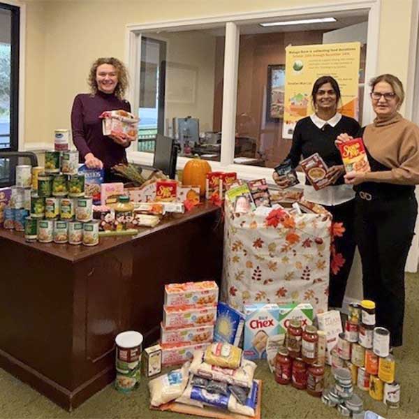 Three women showing Food contiburions for Malaga's food drive