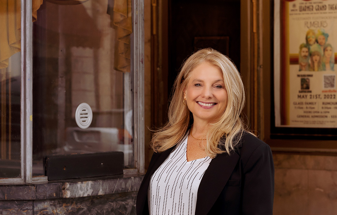 woman standing in front of the warner grand theater