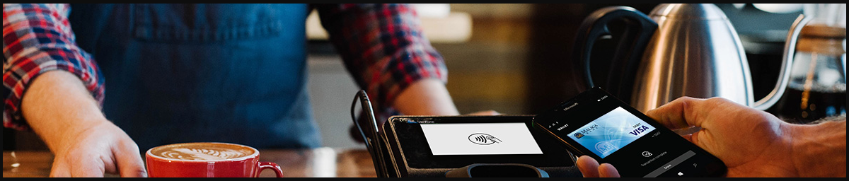 Man in coffee shop using his debit card to tap and pay.