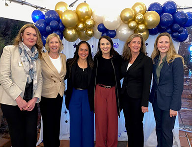 Six women standing in front of balloons