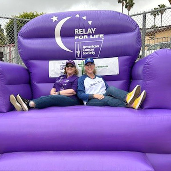 Two women sitting on a giant purple chair