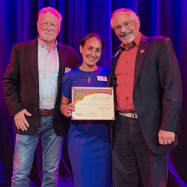 2 men from San Pedro Chamber giving an award to Andrea Lastimos from Malaga Bank