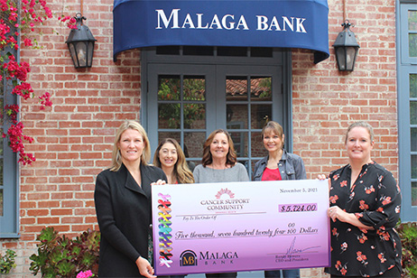 Women from Cancer Support Community and Malaga Bank holding a donation check.